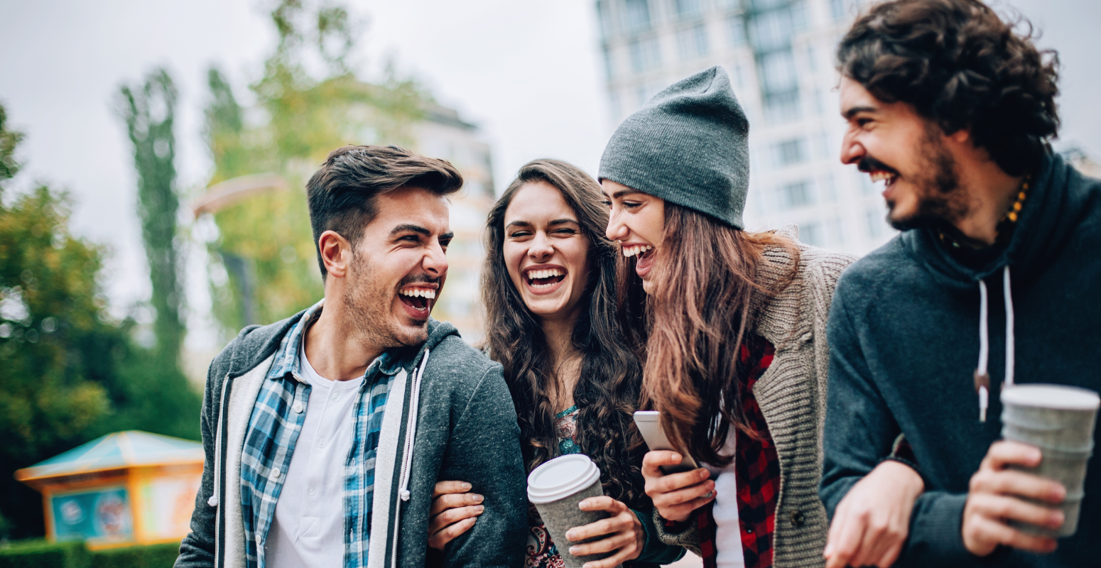 Group of friends laughing and enjoying time together outdoors, representing the social connections fostered through referral marketing campaigns.