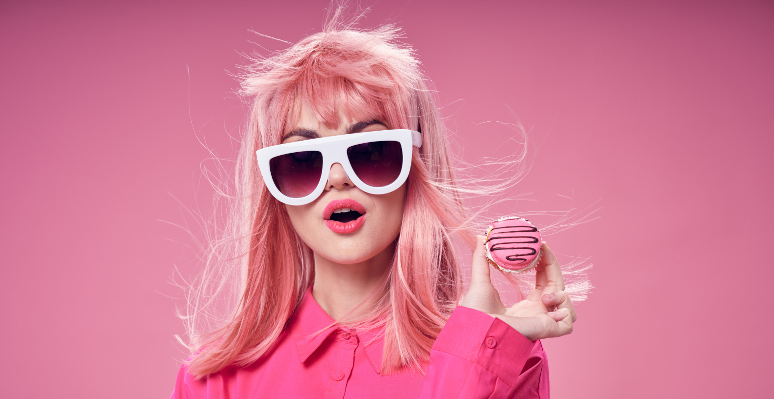 Stylish woman in pink sunglasses and outfit holding a pink frosted cookie, representing bold branding and viral appeal.
