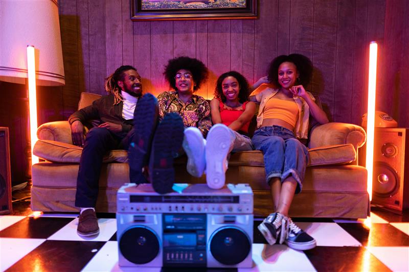 friends on sofa with feet on boombox