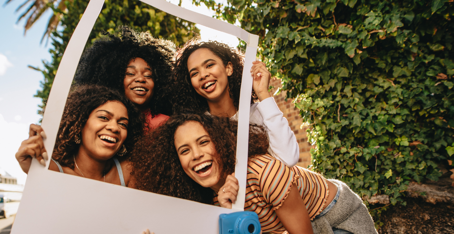 The Science Behind Referral Marketing: What Makes People Share? Girls posing behind a camera cut out, smiling to the camera